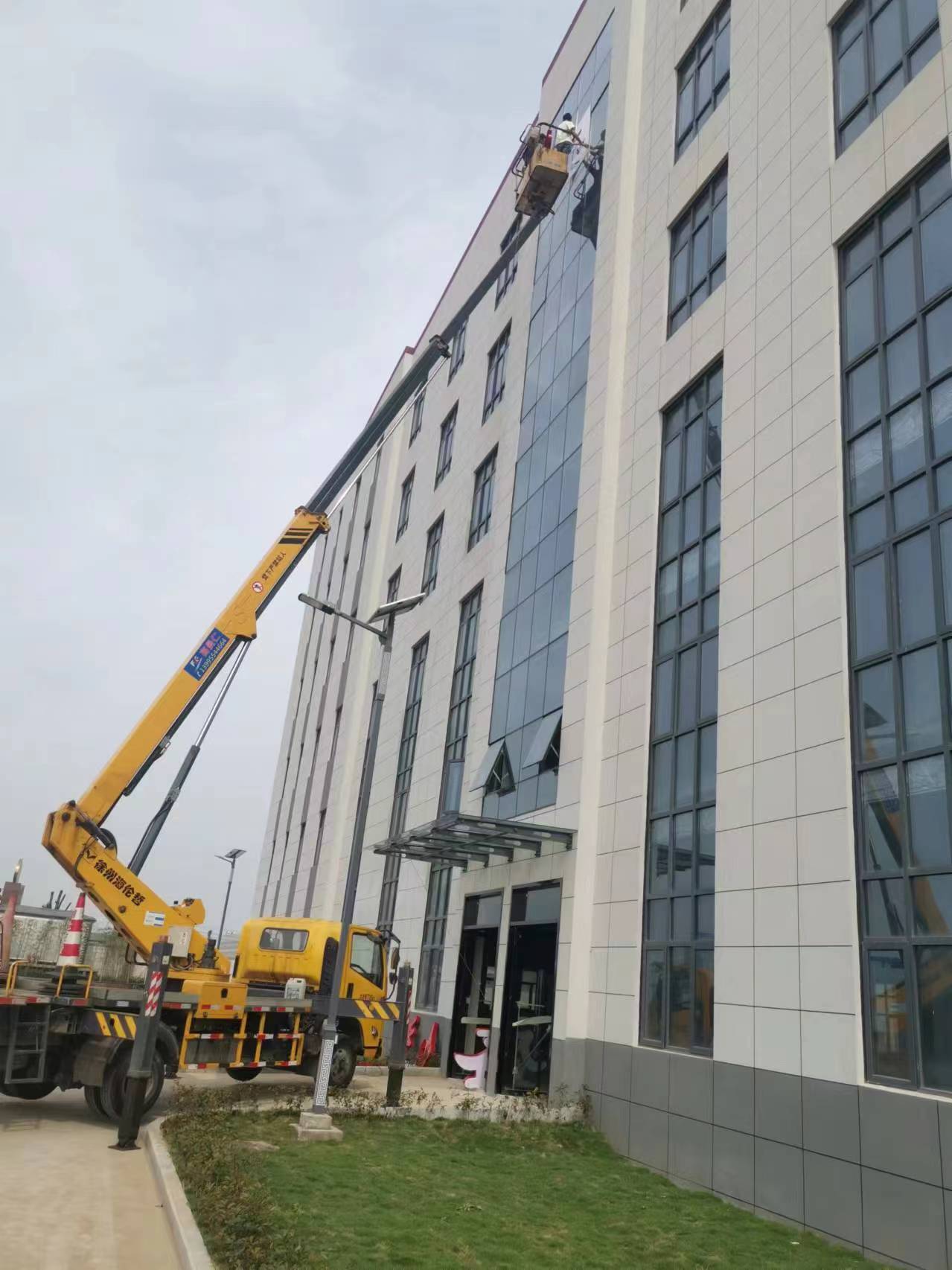 24米升降車高層樓外墻換玻璃施工現(xiàn)場